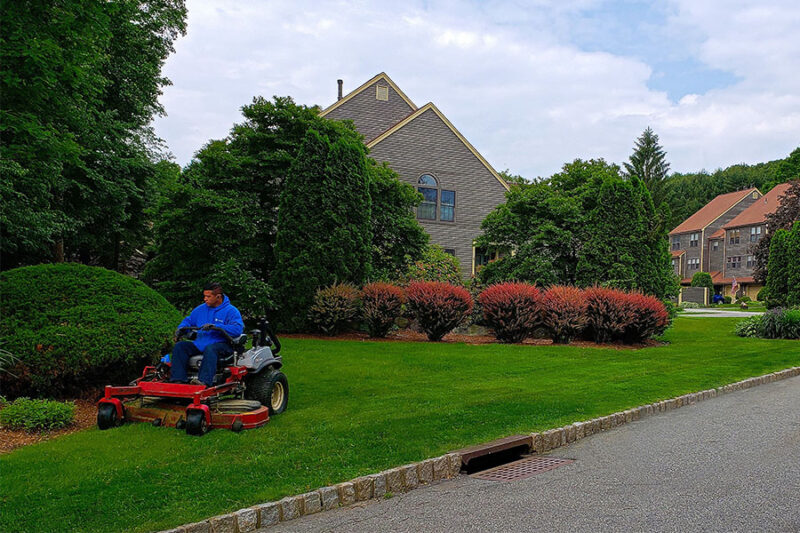 A worker from a commercial property management company in Connecticut diligently maintains the lawn using a powerful lawn mower.