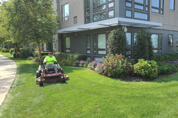 A worker operating a lawn mower vehicle, diligently mowing the lawn at a commercial property.