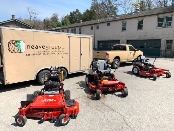 Commercial lawn mowers, a truck, and a trailer from Neave Group, showcasing best practices for landscaping bids preparation.