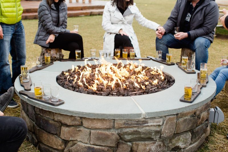 Group of people around a firepit showcasing the inviting and upscale outdoor living space offered by our commercial property enhancement services 