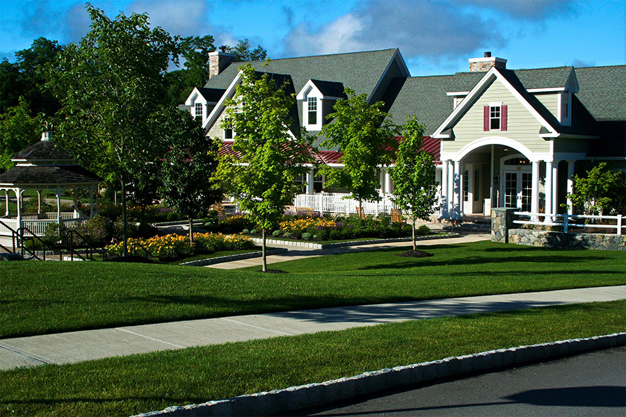 Commercial landscaping for places of worship featuring a lush lawn, trees, and flower beds in front of a large welcoming building