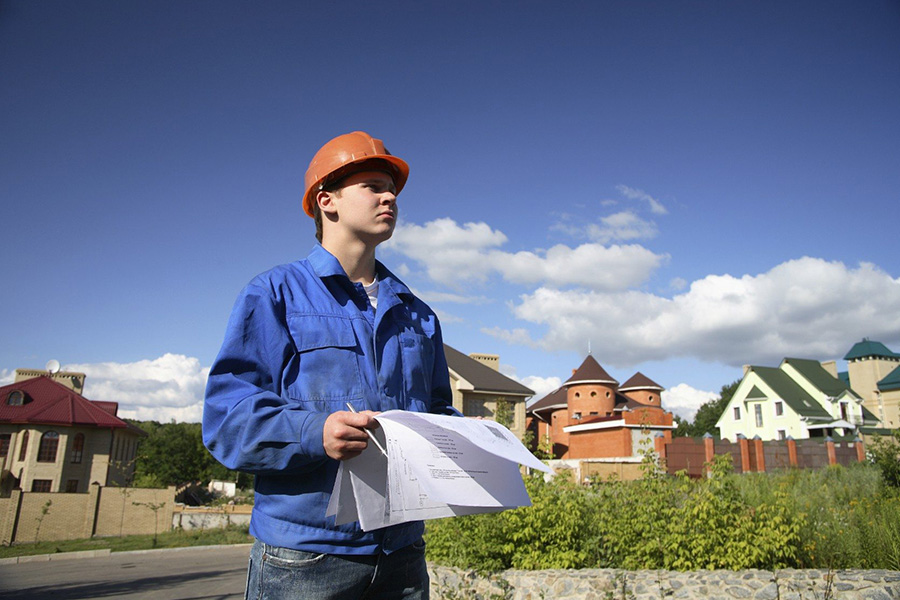 Contractor inspecting plans for seasonal maintenance for commercial properties with buildings and landscaping in the background