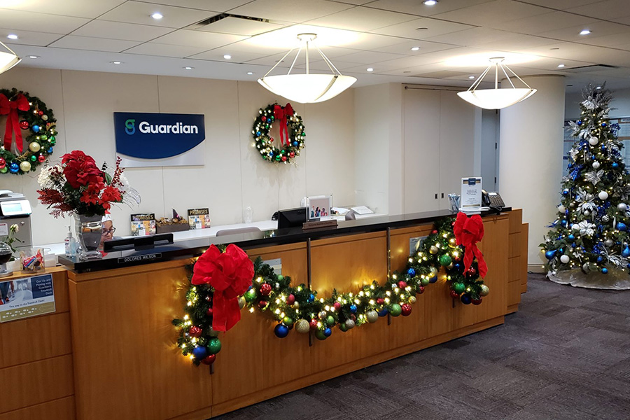 Corporate office reception festively decorated with garlands, wreaths, and a tree, showcasing holiday decorating services