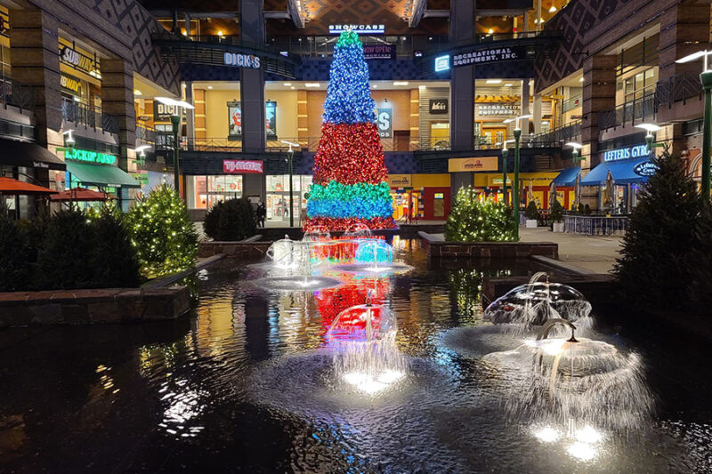 Grand Christmas tree adorned with festive lights as the centerpiece of a bustling mall complex