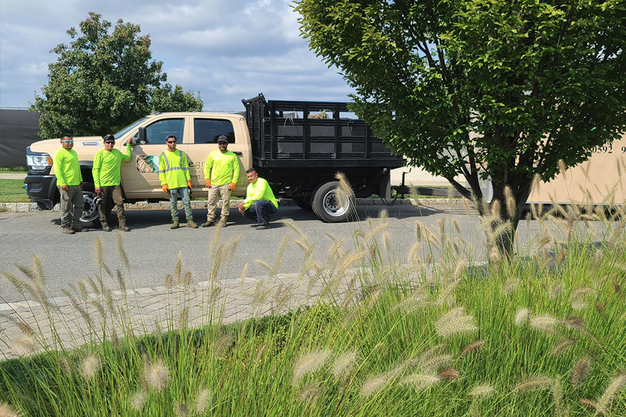 Groundskeeping experts resting near a Neave Group company vehicle after completing office campus landscaping work