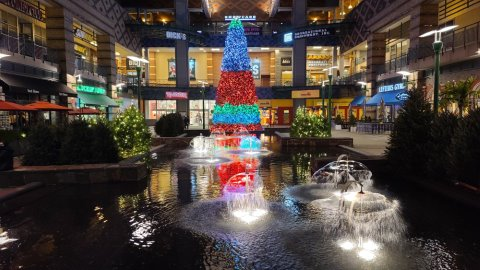 Giant Christmas tree decorated with custom holiday lighting and pine cones at the mall.
