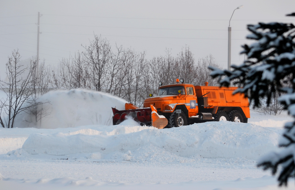 Orange snowplow truck clearing snow as part of disaster preparedness for businesses during winter conditions.