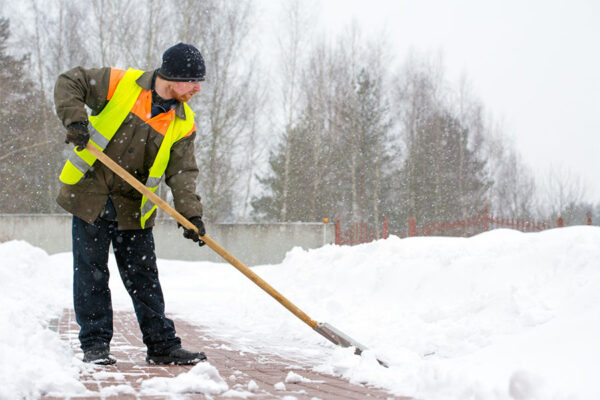 Worker shoveling to clear snow from the commercial property after snowfall ends