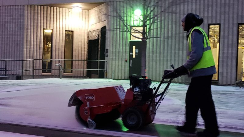 Worker clearing snow on sidewalks of the establishment.