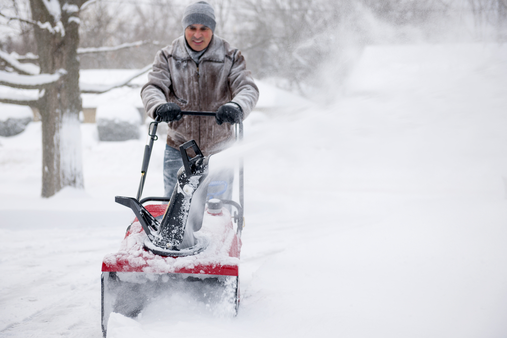 Man using snowblower to clear deep snow on commercial properties as part of the snow plowing contract.